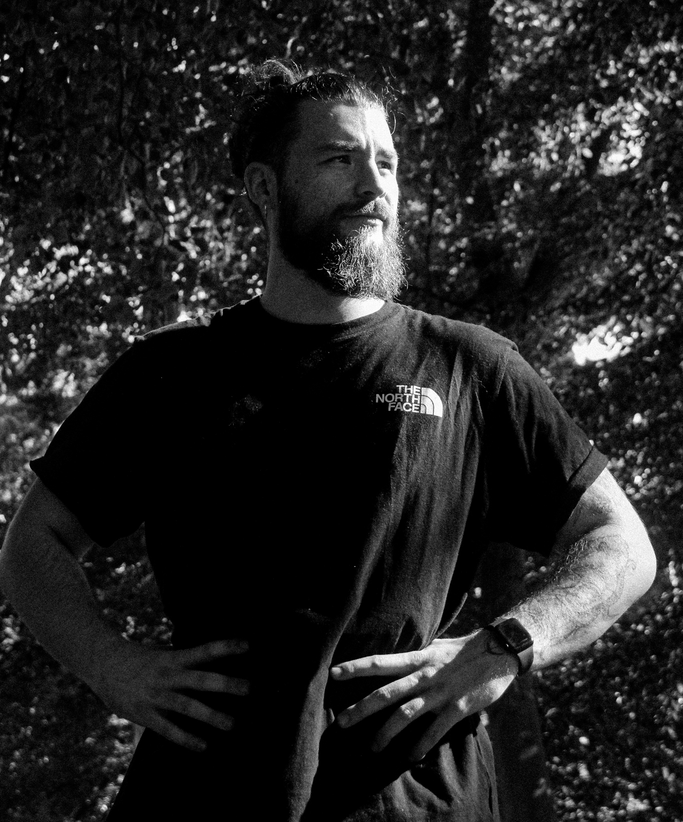 Portrait en noir et blanc d'Emeric Solon, coach sportif, en tenue The North Face dans le Bois de Vincennes
